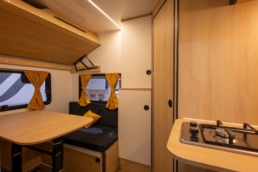 Interior de la caravana VDK 260 con comedor, armarios y placa de cocción