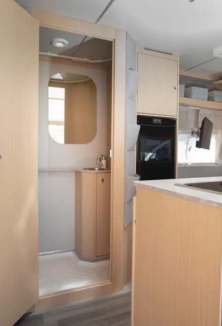 Baño de la VDK V400L con lavabo y espejo, visto desde la cocina