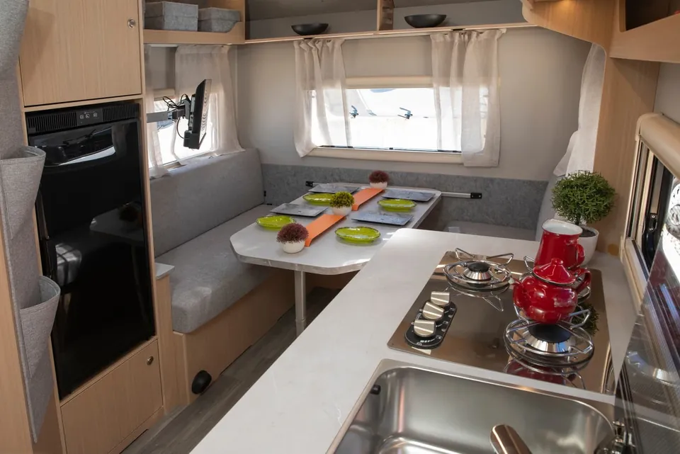Interior de la caravana VDK V400L con comedor, cocina de dos fuegos y nevera